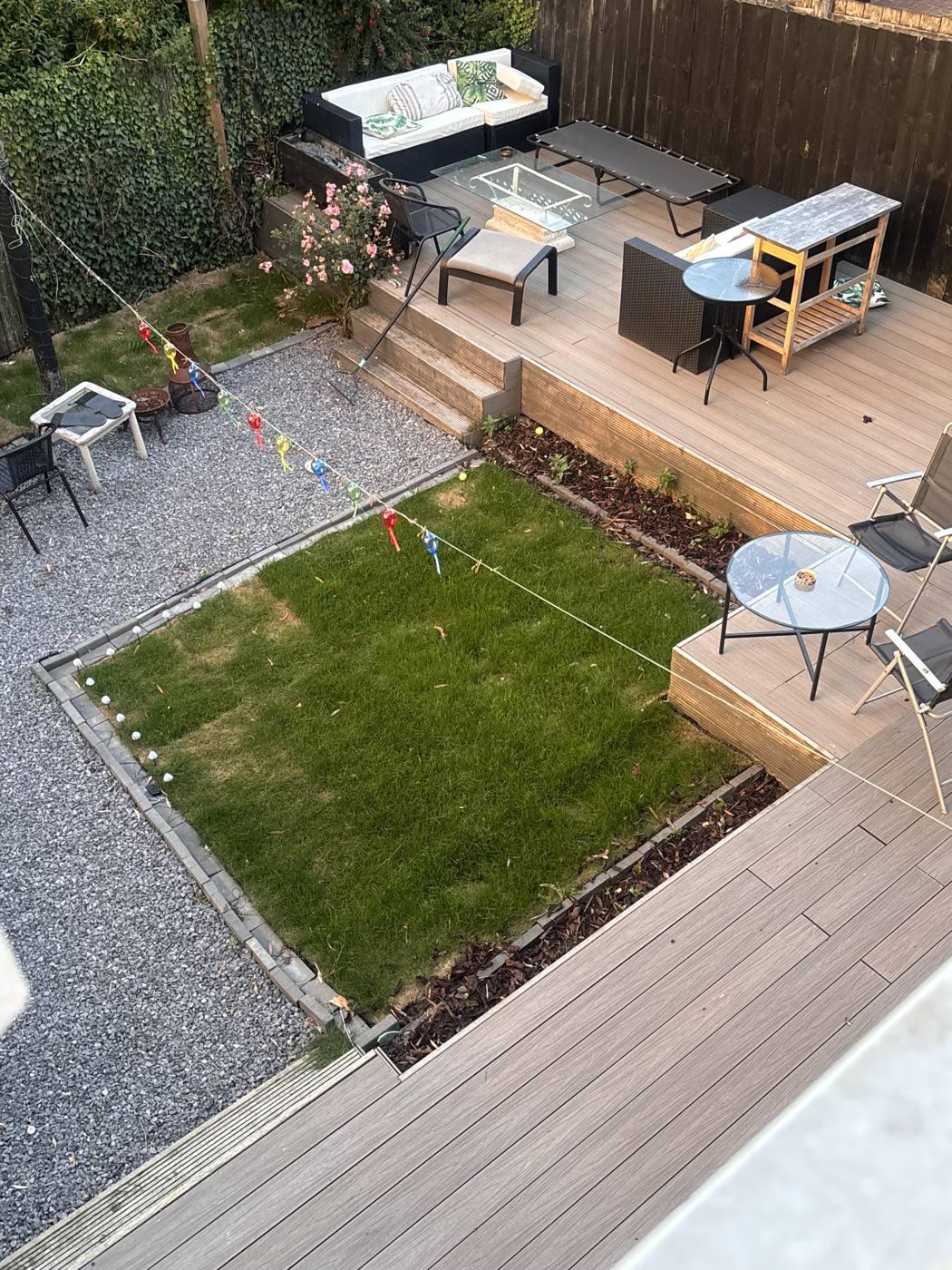 View from above of a back garden in Sunderland with a raised composite deck, outdoor seating, a square lawn edged in gravel and bunting strung across.